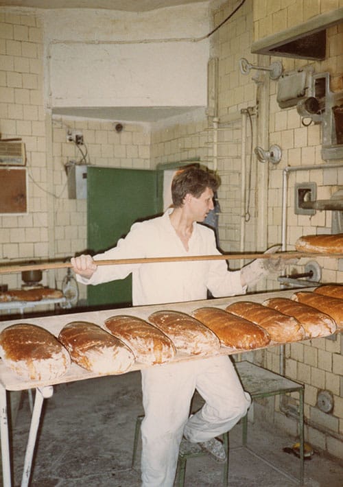 Piekarz wyjmujący chleb z pieca / A baker taking bread out of the oven